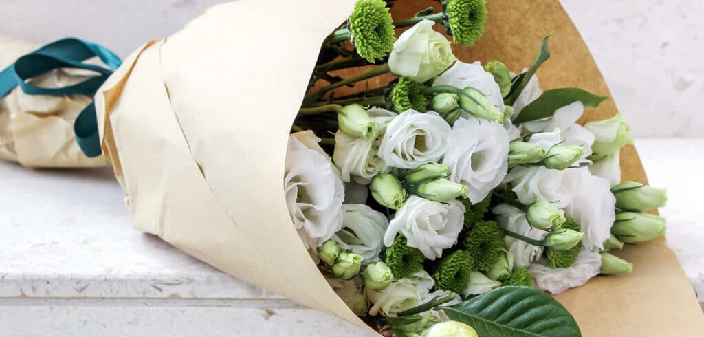 Ramo de rosas blancas con plantas decorativas verdes