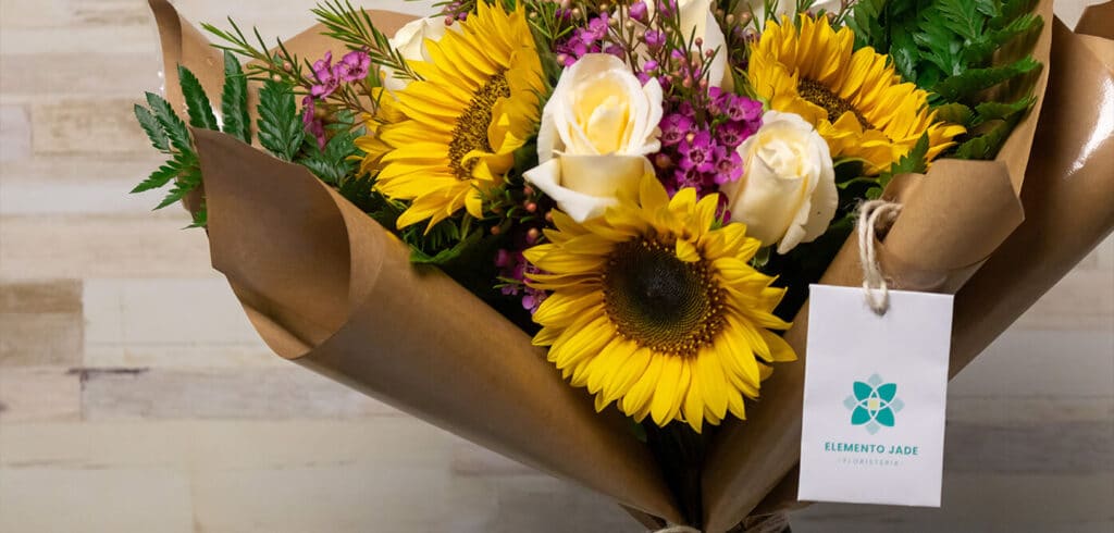 Ramo de flores que contiene girasoles, rosas blancas, gerberas y detalles.